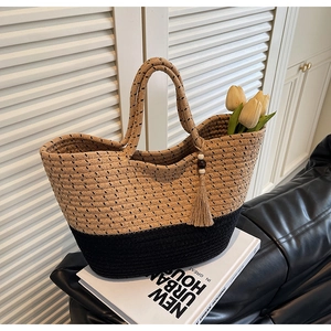 Detail of bicolor woven tote with polka dots and decorative tassel on a white book