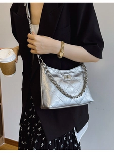 Silberne Stepptasche mit Metallkette, getragen als Umhängetasche von einem Model