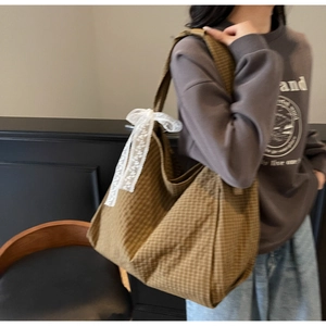 Detailed shot of brown checkered tote bag featuring a white lace bow decoration