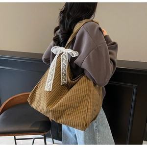 Detail of large check tote bag featuring a white lace bow on the shoulder strap