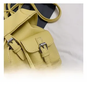 Close-up of silver metal buckle and stitching on light yellow pebble leather bag