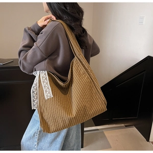 Brown checkered tote bag with lace ribbon detail shown worn on shoulder in room
