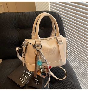 Macro detail of beige leather pillow bag with textured embossing and colorful charms