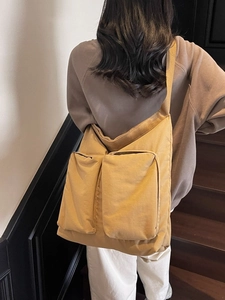Large mustard yellow canvas tote bag with dual front pockets and wide shoulder strap