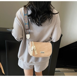 Detail of light beige suede crossbody bag with ethnic style floral woven wide strap