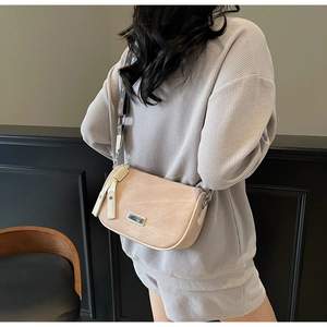 Beige crescent bag with ethnic pattern wide strap shown from a side view on a model