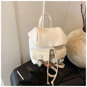 Close-up of white pebble leather mini backpack showing metal buckles and pocket details