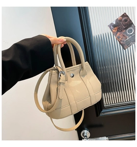Detail of beige lychee texture mini tote bag with silver snap button and shoulder strap