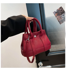 Detail of red litchi texture leather tote bag with silver hardware and shoulder strap