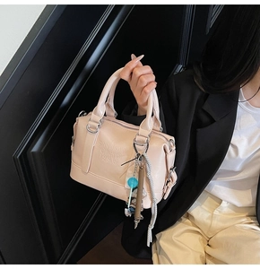 Detail of light pink Boston bag with embossed lettering and blue lollipop charm handle