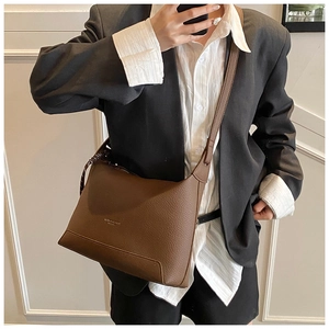 Close-up of brown litchi pattern leather tote bag with subtle gold logo and shoulder strap