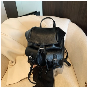Detail of black pebbled leather backpack with silver buckles and drawstring closure