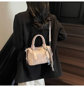 Pink Boston handbag detail with ENJOY LIFE embossing and braided doll charm