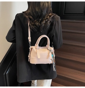 Detail of pink faux leather handbag with embossed letters and woven rope pendant on stairs
