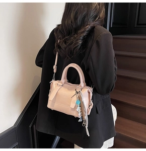 Pink Boston bag with detachable strap and brand logo shown on a model on stairs