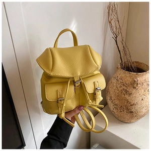 Detail of yellow pebbled leather mini backpack with drawstring and buckle pockets