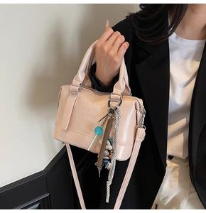 Detail of light pink Boston bag with ENJOY embossed text and decorative charms