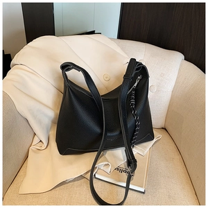 Detail of black lychee grain leather tote bag with braided tassel and shoulder strap