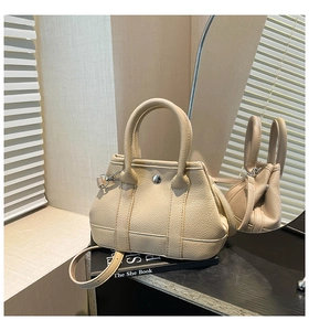 Detail of cream leather handbag with lychee texture and silver metal twist lock closure