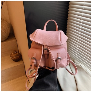 Detail of pink pebbled leather mini backpack with silver metal buckles and flap pockets