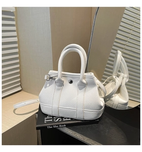 Detail of white litchi grain leather bucket bag with metallic buckle and sturdy handles