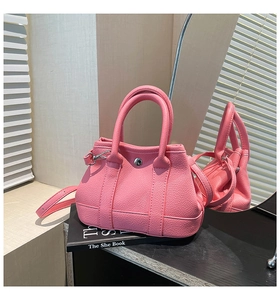Detail of pink lychee leather bucket bag featuring silver twist lock and dual handles