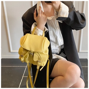 Close-up of a yellow lychee texture backpack on a model in a minimalist modern setting