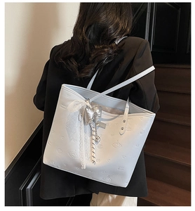 Detailed close-up of light blue tote bag featuring heart embossing and lace bow charm