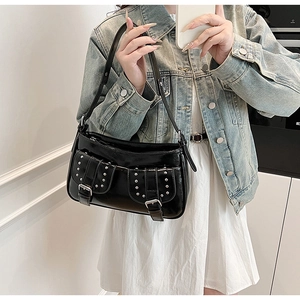 Detail of black glossy punk shoulder bag with silver studs and adjustable strap