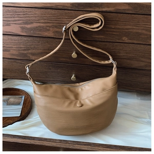Detail of caramel crescent crossbody bag featuring an adjustable strap and zip closure