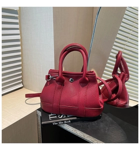 Detail of red lychee grain leather bucket bag with silver buckle and round handles