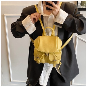 Detail of yellow mini backpack with lychee texture and three-pocket design shown by model
