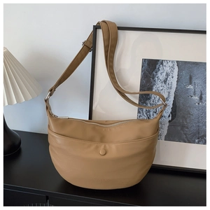 Macro detail of khaki crescent bag showing smooth leather texture and embossed logo