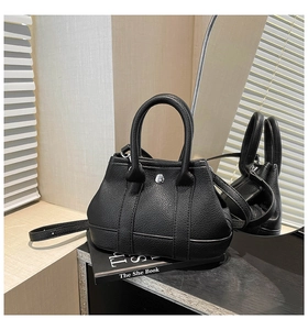 Close-up of black litchi grain leather bucket bag with silver metal buckle and strap