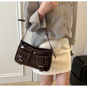 Detail view of brown vintage motorcycle shoulder bag with silver buckles and stud pockets