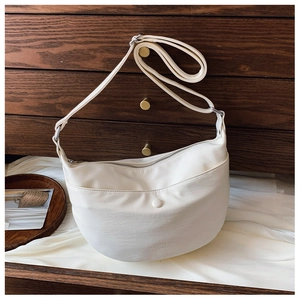 Detail view of cream dumpling bag with lychee texture leather and top zipper closure