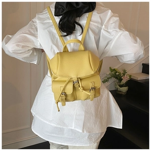 Detail of yellow lychee leather mini backpack worn by model in a cozy indoor setting