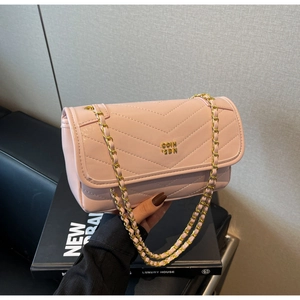 Detail of pink oil wax leather crossbody bag with V-quilted stitching and gold chain