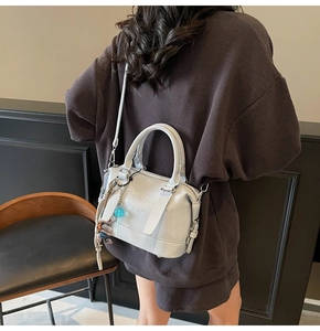 Back view of model wearing light blue Boston bag with leather finish and logo detail