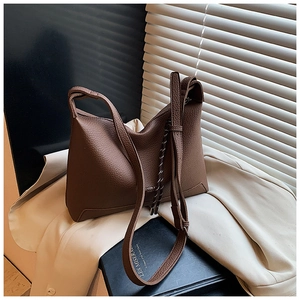 Close-up of coffee brown lychee pattern leather bag with woven strap on aesthetic background