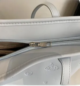 Close-up of smooth metal zipper and textured blue leather tote with embossed logo