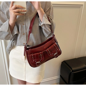 Mirror selfie showing a deep red shiny leather shoulder bag with silver rivet details