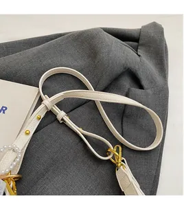 Détail de la bandoulière en cuir blanc cassé avec perles et mousquetons dorés
