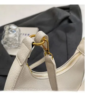 Détail d'un sac hobo en cuir blanc montrant les crochets dorés et le grain cuir