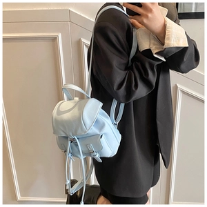 Detailed view of light blue leather mini backpack with flap closure on black blazer