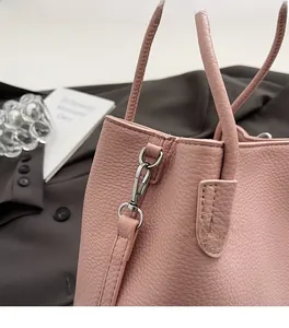 Detail of pink lychee grain leather handbag featuring precision stitching and silver hardware