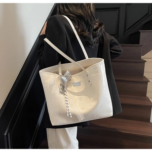 Close-up of cream tote bag with embossed texture, silver bow and lace detailing