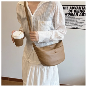 Detail of tan dumpling bag with lychee pattern texture and magnetic front pocket