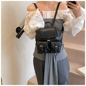 Detail of black pebbled leather mini backpack with dual front pockets and silver buckles