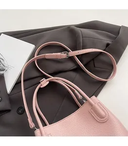 Detail of pink lychee leather texture and silver hardware on a bucket shoulder bag